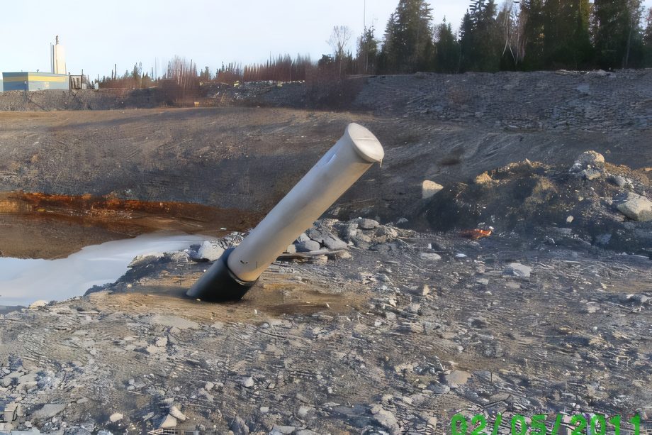 Un conduit d’acier qui sort du sol à angle sur un chantier de gravier
