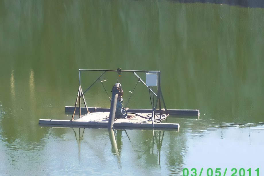 Une pompe installée sur un flotteur dans l’eau verte de la fosse