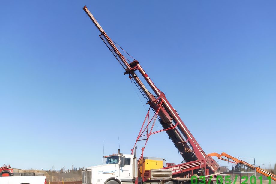 Le mât d’une foreuse incliné contre le ciel, camion blanc au sol, forage à angle en Abitibi