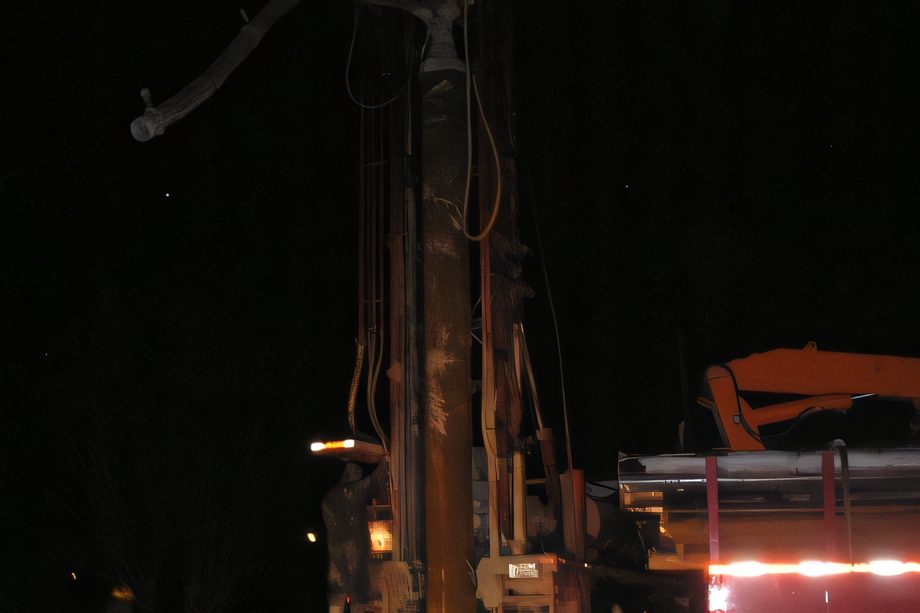Une foreuse éclairée la nuit, projecteurs allumés sur le mât